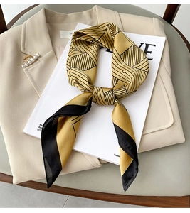 Detail of a ginger and black geometric silk scarf with a gold pearl ring accessory