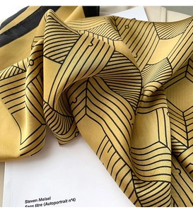 Detailed macro view of mustard yellow satin square scarf with modern black geometric lines