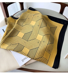 Detailed view of geometric pattern silk scarf with yellow and black artistic design