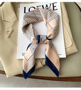 Detail of elegant silk scarf tied as a neck accessory on khaki blazer with jewelry