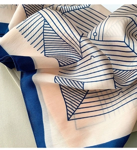 Detail of silk-like neckerchief showing navy geometric lines and soft satin texture