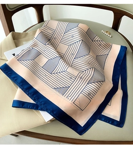 Detailed close-up of geometric silk scarf in orange and navy blue on soft chair