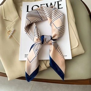 Silk-like geometric pattern square scarf in orange and navy blue on a beige blazer