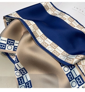Detail of silk scarf with blue and gold color block design and letter patterns