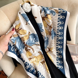 Close-up of floral silk scarf with blue and tan blossom patterns and rope trim