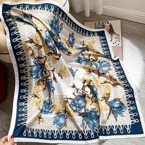 Detail of elegant floral silk scarf with magnolia prints and blue satin borders on faux fur