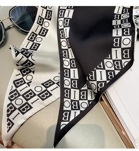 Detailed view of black and white checkered silk scarf with letter print on a stylish desk