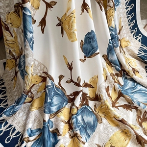 Detail of floral print scarf with blue and yellow patterns on smooth satin fabric