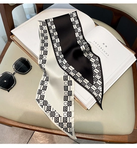 Detail of silk-like neckerchief with black and white letter print on a leather surface