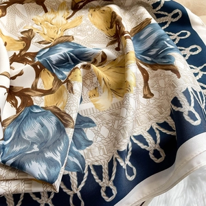 Detail of floral printed square scarf with rope patterns on soft plush background