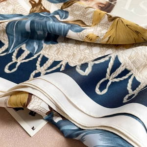 Detail of silk scarf with floral prints and woven rope patterns in blue and gold
