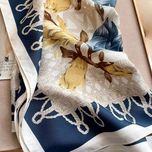 Close-up of floral silk square scarf with navy borders and elegant draped texture