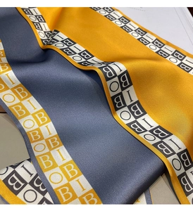 Macro shot of silk scarf with ginger and navy blue color blocks and letter patterns