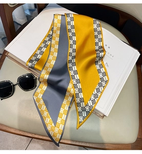 Detail of yellow and grey satin scarf with geometric letter print on a white book