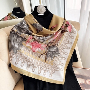 Close-up of elegant floral print silk square scarf with golden border and satin finish