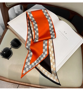 Detail of orange satin scarf with letter prints and plaid edge on white book