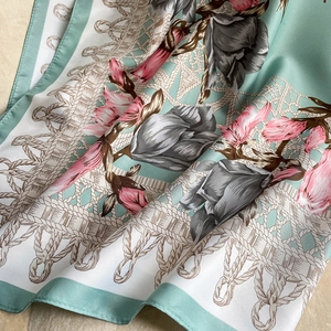Detail of silk-touch floral scarf with mint green borders and elegant draped texture