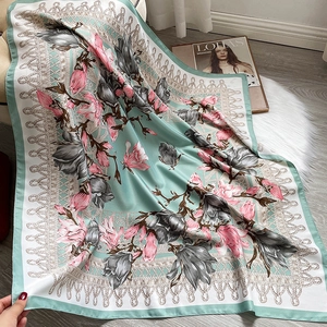 Detail of floral silk scarf with magnolia prints and mint green borders on soft rug