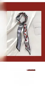 Détail d'un foulard étroit en soie de style français avec imprimé floral rouge sur blanc