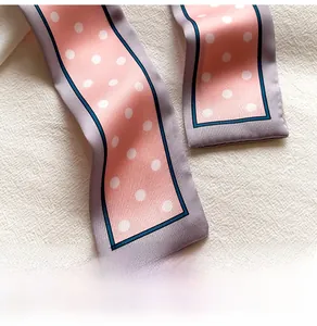 Détail d'un foulard en soie à pois roses et gris avec d'élégants bords bleu marine