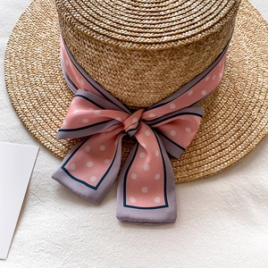 Détails du chapeau de paille plat avec ruban de soie à pois roses et nœud élégant