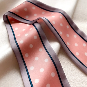 Gros plan du foulard en soie rose à pois avec bords contrastés gris et bleu marine