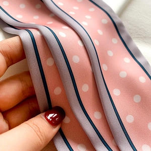Gros plan d'une écharpe en satin rose clair à pois blancs et texture soyeuse fine