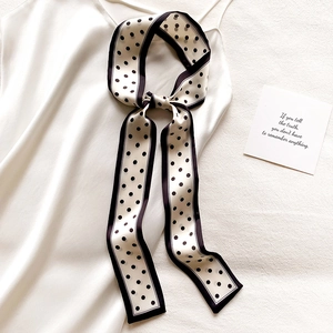 Élégant foulard fin en soie à pois pour femme noué sur une robe en satin blanc