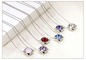 Detailed display of square zircon pendants in six birthstone colors on a white pedestal