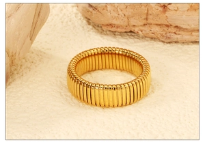 Macro shot of gold-plated stainless steel ring with vertical ribbed texture on a stone base