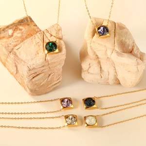 Golden square pendant necklaces with colorful round gemstones on natural stone background