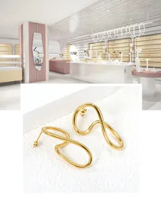 Close-up of golden irregular wave stud earrings with minimalist abstract metal lines