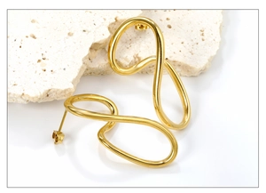 Detail of gold-plated irregular abstract stud earrings on white travertine stone