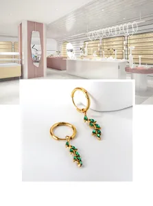 Detail of gold leaf earrings with green emerald zircon dangles and circular clasp