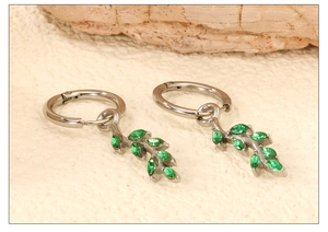 Detailed view of silver leaf earrings featuring sparkling marquise green zircons