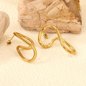 Minimalist irregular gold wavy stud earrings with polished finish on textured background
