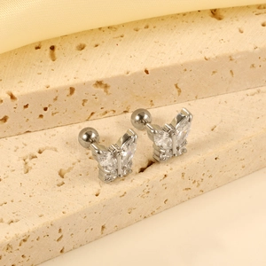 Sparkling butterfly stud earrings with clear zircon stones on textured stone display