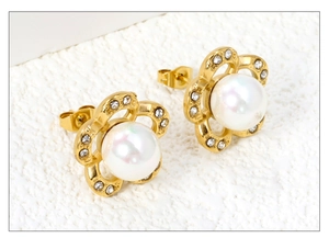 Detail of floral gold earrings with center pearl and sparkling rhinestone edges