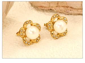 Macro shot of gold flower earrings with white pearl and sparkling pavé crystal petals