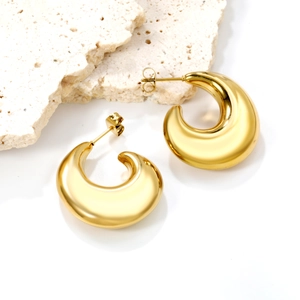 Minimalistische dicke tropfenförmige goldene Edelstahl-Ohrringe auf Steinfläche