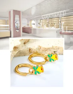 Nahaufnahme goldener Edelstahl-Creolen mit grün-gelben Emaille-Glockenanhängern