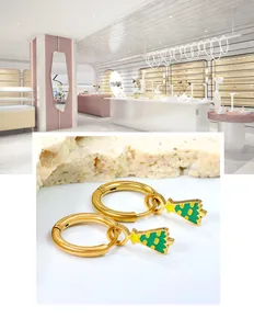 Vue détaillée de boucles d'oreilles sapin de Noël dorées avec étoiles sur support