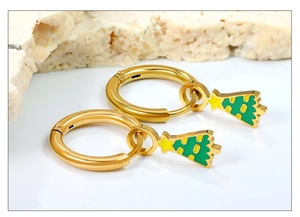 Détail de boucles d'oreilles créoles sapin de Noël dorées avec émail vert et étoile