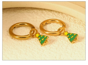 Détail de créoles dorées avec pendentifs sapin de Noël vert et étoiles jaunes