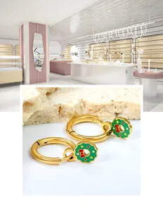 Gros plan de boucles d'oreilles couronne de Noël dorées avec nœud rouge et feuillage