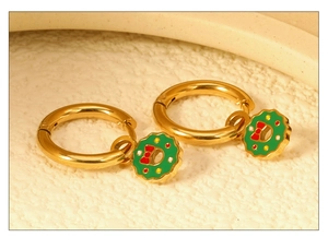 Gros plan de boucles d'oreilles couronne de Noël dorées avec nœud rouge et émail