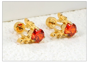 Vue macro des boucles d'oreilles renne en acier doré avec zircons rouges scintillants