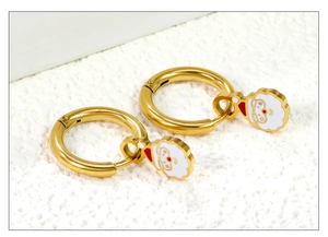 Macro shot of gold-plated hoop earrings with red and white enamel Santa Claus charms