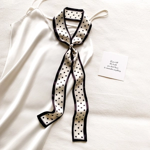 Foulard étroit à pois avec boucle en perle sur un tissu en soie blanche lisse