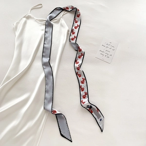 Détail d'une robe en satin blanc avec un ruban de soie gris à fleurs noué à la taille